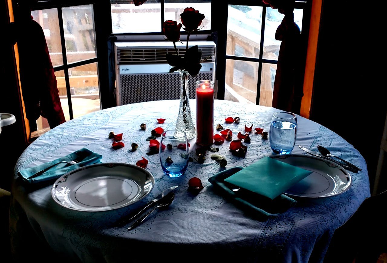 A beautifully set table with a candle and rose petals, creating an intimate ambiance.