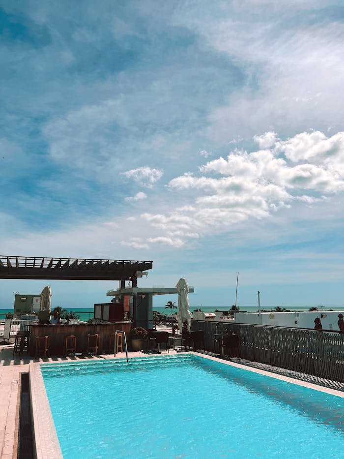 A vibrant rooftop pool overlooking the ocean on a sunny day.